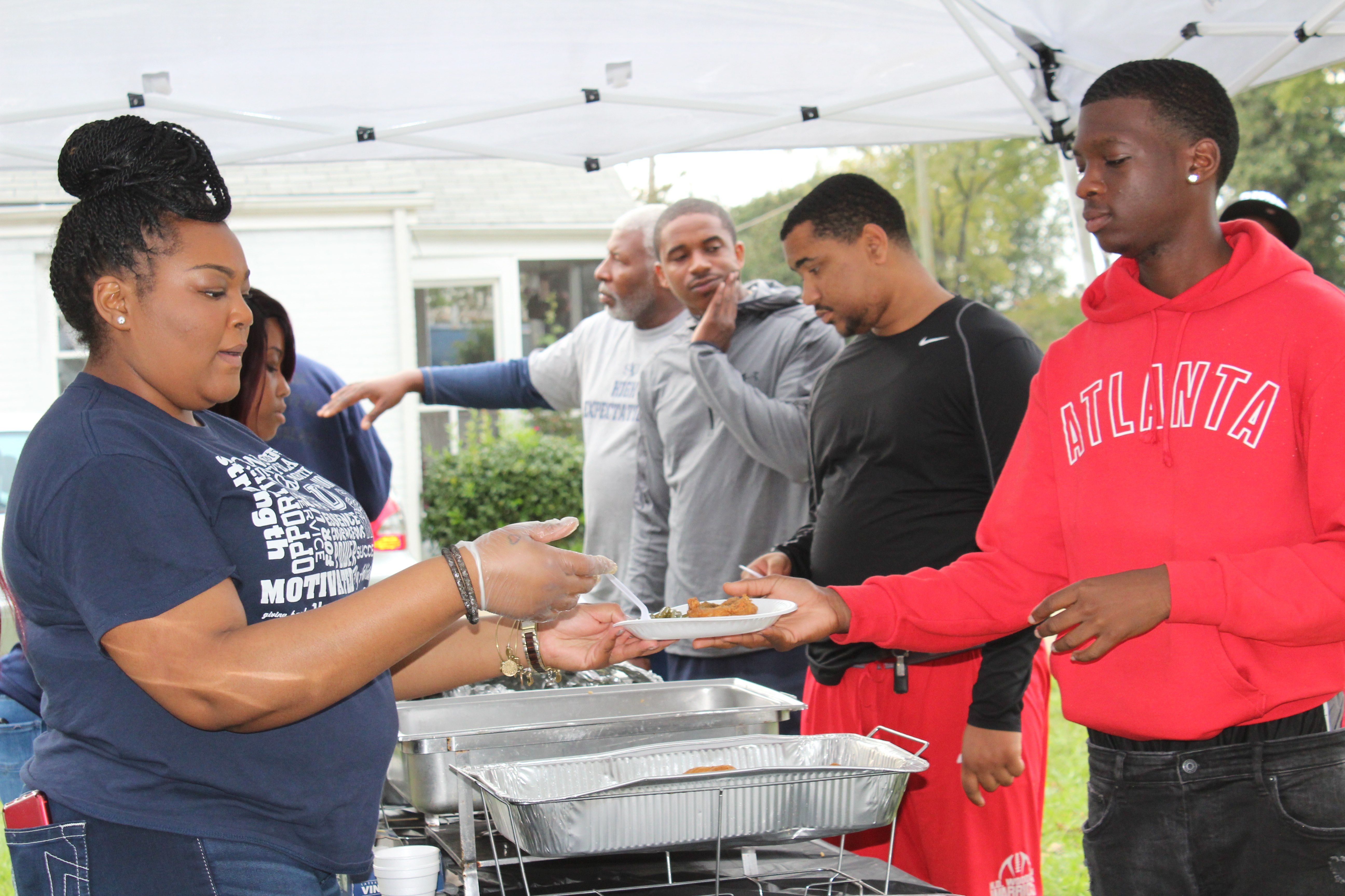 Line of students getting plates of fish from alumni